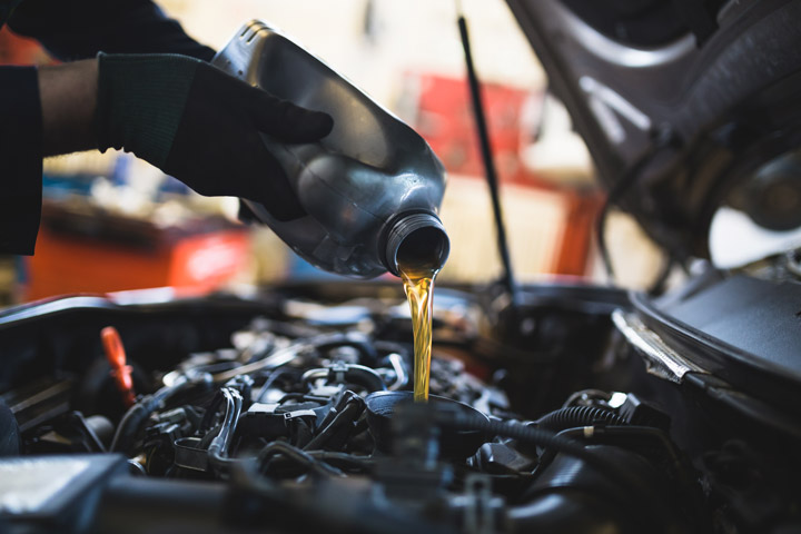 Mechanic adding oil to car
